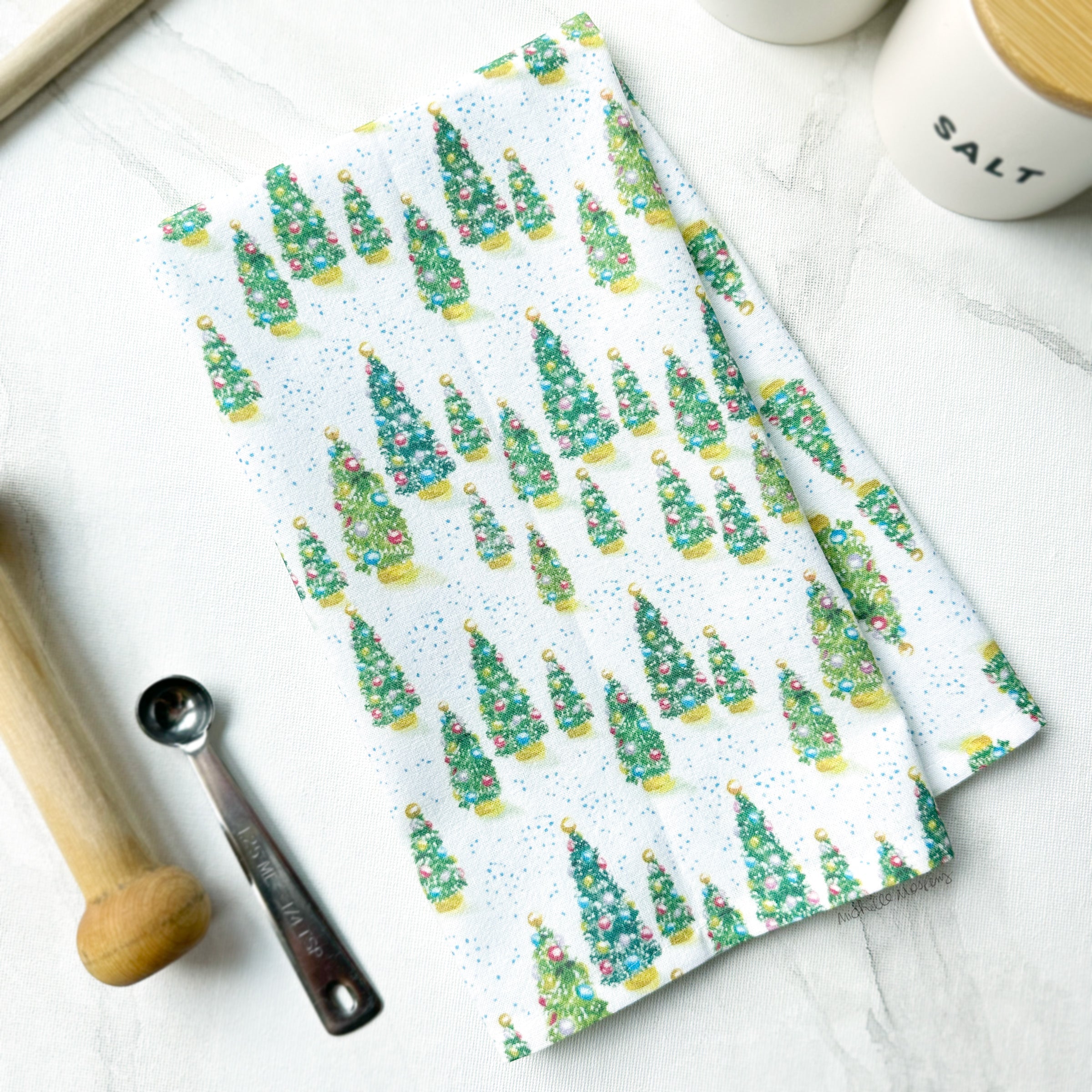 Cotton tea towel with watercolor christmas trees artwork printed in full color. Christmas trees have colorful ornaments and snow falling. Cute hostess towel Christmas gift.